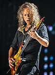 Man with long hair playing electric guitar onstage at a concert