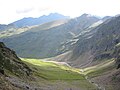 Les pâturages du grand replat de la vallée de la Géla éclairés par le soleil. Au-dessus, sous le pic de l'Aiguillete, le vallon qui descend du Port Vieux et où se situent les mines de la Géla.