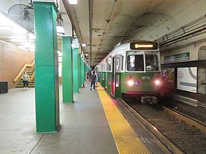 A green light rail train at an underground station