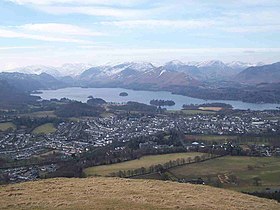 View of lake surrounded by mountains, seen from a mountain peak