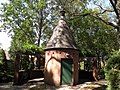 A garden building with an overhead trellis around part of it.