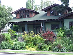 Photograph of a Craftsman bungalow with larger dormers, porch, and fieldstone steps.