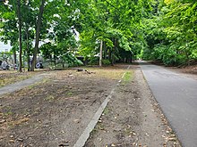 A bike trail in a suburban area with a line of stone in the ground next to it