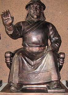 A statue of a man sitting with arm outstretched on a chair