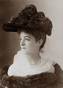 young woman in semu-profile, wearing a large and ornate hat