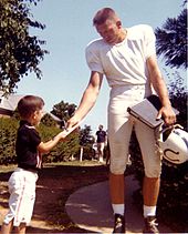 Unitas bending down to above an autograph to a child