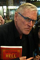 A man is holding a book and humorously glaring at the camera