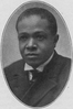McCants Stewart, a young clean-shaven African American man wearing a double breasted suit with a white shirt with wing collar and tie