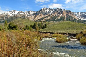 A midsized stream flowing beneath snow-capped mountains