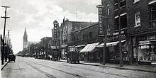 Black and white street scene with storefronts, circa 1930