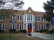 an old two story brick building with an orange doors and blue banners