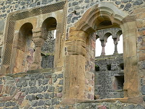 Münzenberg Palace has walls of rubble but refined detailing in its windows, the triple arch of the door and the gallery seen beyond which opens onto a vista.