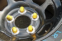 Five yellow lug nuts for use on a car with wheel studs