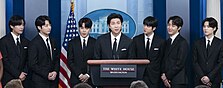 BTS members speaking in front of a White House lectern