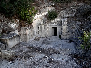 כניסה למערת קבורה בבית שערים. בפתח המערה רואים את דלת האבן שסגרה את הכניסה למערה שעוצבה בדומה לדלת עץ.