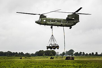 A Dutch CH-47 hauls slung light vehicles and a load on exercises, 2015