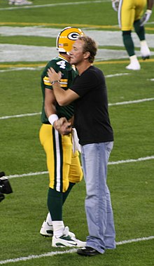 Majkowski in street clothes on a football field shaking Brett Favre's hand