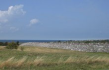 Un long mur traversant le paysage, avec la mer en arrière-plan