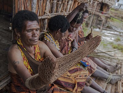 Para mama papua sedang membuat tas noken