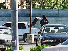 Mătăsăreanu standing behind the white Chevrolet Celebrity that was driven to the robbery.