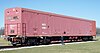 A large, dull red railcar on four sets of wheels sits on a short section of track