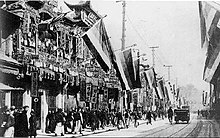 Black and white street scene with multiple buildings hanging Five Races Under One Union flags used by the rebels of the 1911 Revolution