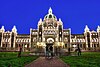 Lights outline the Legislature buildings of British Columbia at twilight.