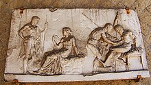 bas-relief, à gauche, Hercule nu debout devant une femme assise ; à droite, un soignant penché au-dessus de la cuisse d'un blessé assis