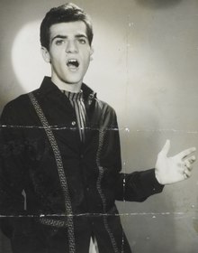 A black and white photo of a young man singing.