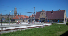 Photo de la gare, montrant les voies et quais, ainsi que le bâtiment.