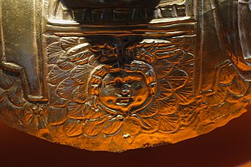 Face surrounded by scales on the torso of the bust.