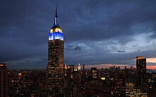 The Empire State Building as seen at night, illuminated in blue and white
