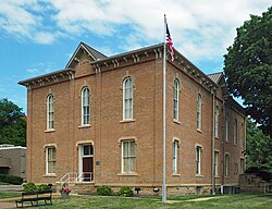 A boxy, two-story brick building fronting a small plaza