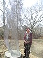 Artist Susan Mohl Powers standing by her perforated metal sculpture, "Dancing Galaxy"