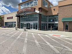 A set of automatic doors leading into a shopping mall. Above the doors is the text "University Park Mall" in white text on a brown arch.