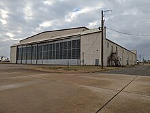 A large tan metal aircraft hangar with two large rollback doors