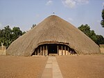 A wooden conical building covered by reeds