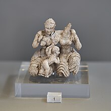 Ivory figurine showing three figures; two seated women and a child between them