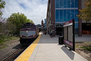A train at a curved railway platform next to a parking garage