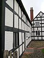 Frontage of the 16th-century farm, adjoining the 19th-century structure, seen in the background. The older building is genuinely timber framed, although the outer skin has been replaced with brick.