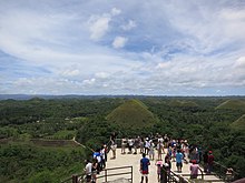 People on an observation deck overlooking hills