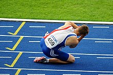 Athlète à genou et se prenant la tête à deux mains, après une disqualification.