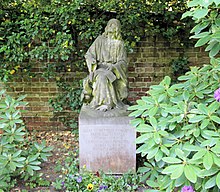 A moss-covered gravestone, in the shape of a seated woman.
