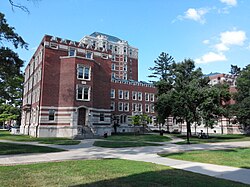 A U-shaped brick and stone building with a nine-story tower at its back on a clear summer day