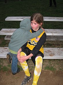 A small child hugs an older, injured child