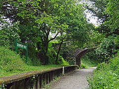 The Camel Trail passing through the disused partially-restored Dunmere Halt, under a bridge that carries road traffic through the hamlett