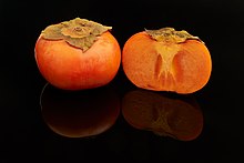round, orange-coloured fruits, one whole and one cut in half