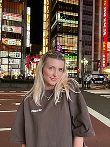 Olivia D. Novak standing and smiling to the camera at night time in Shinjuku, Japan in 2023.