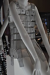 Photo d'une robe composée de tuiles de métal blanc portée par un mannequin en plastique blanc.