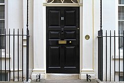 A white building with a black door, with the number eleven on the door